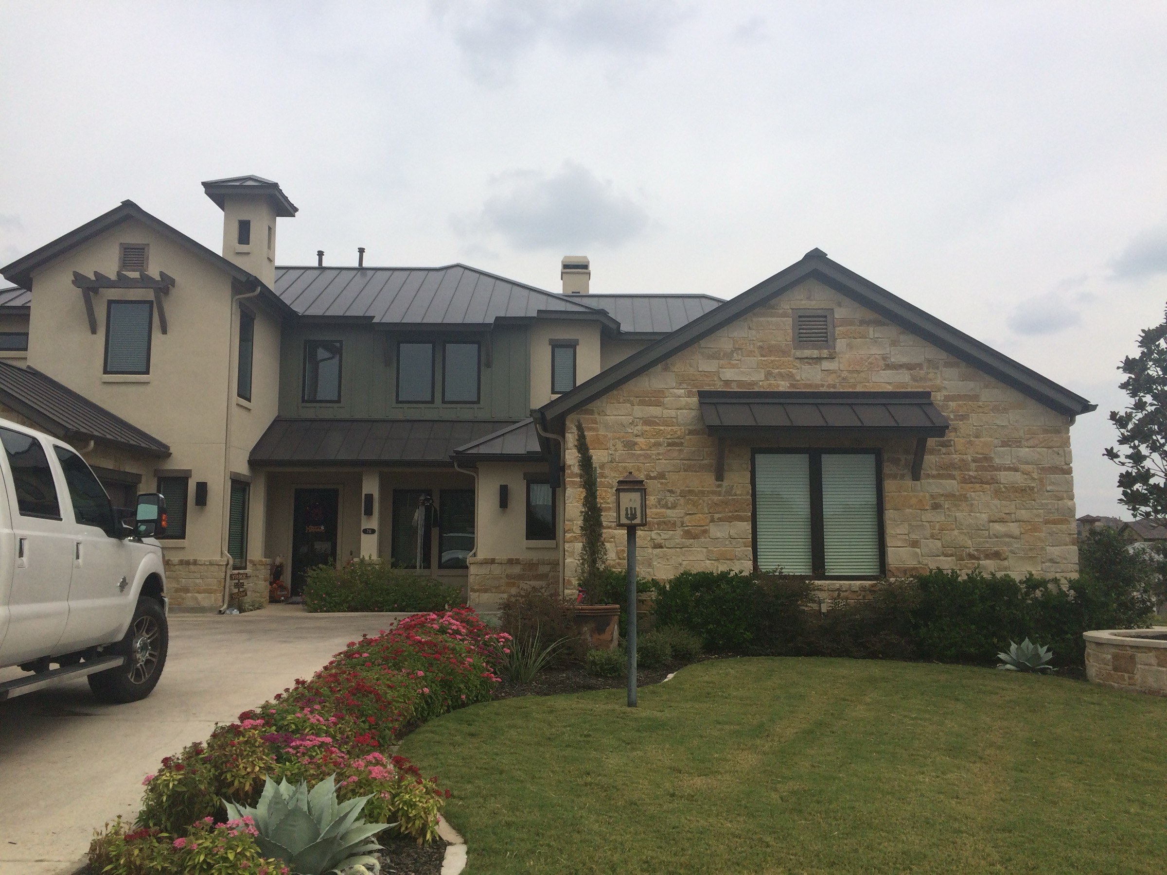 Limestone Central Texas home with a completed dark standing-seam metal roof