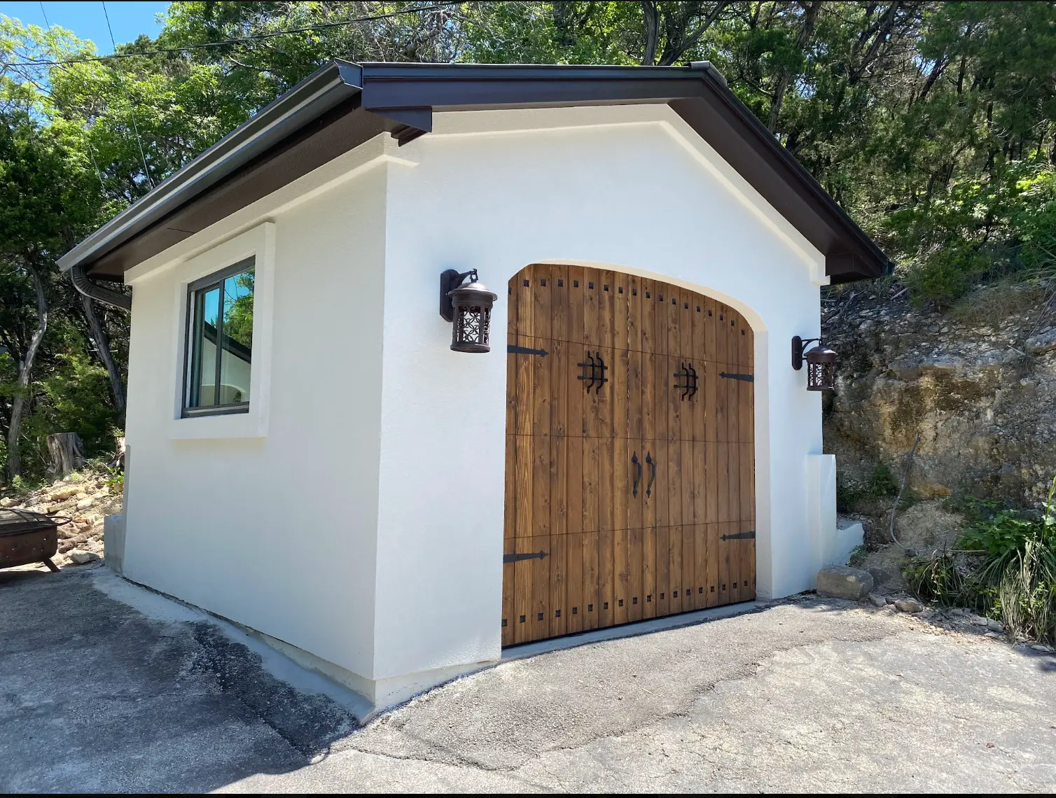 Custom detached garage with wood doors and stucco finish built by TWT on a finished Central Texas property