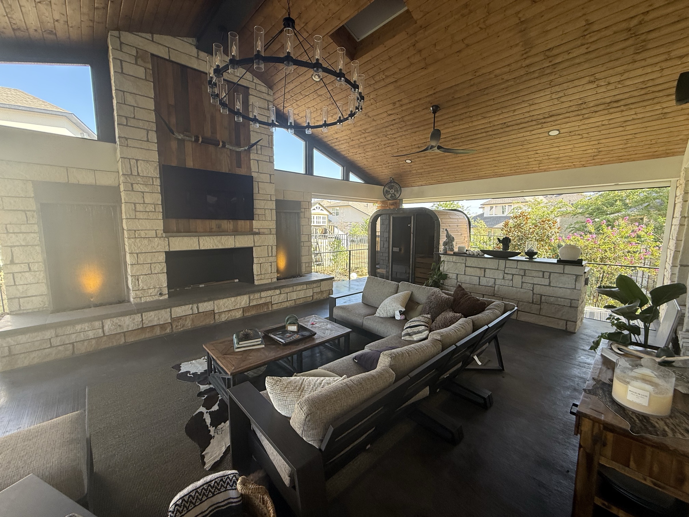 Finished vaulted Rough Hollow living room with a stone fireplace, chandelier and lounge seating
