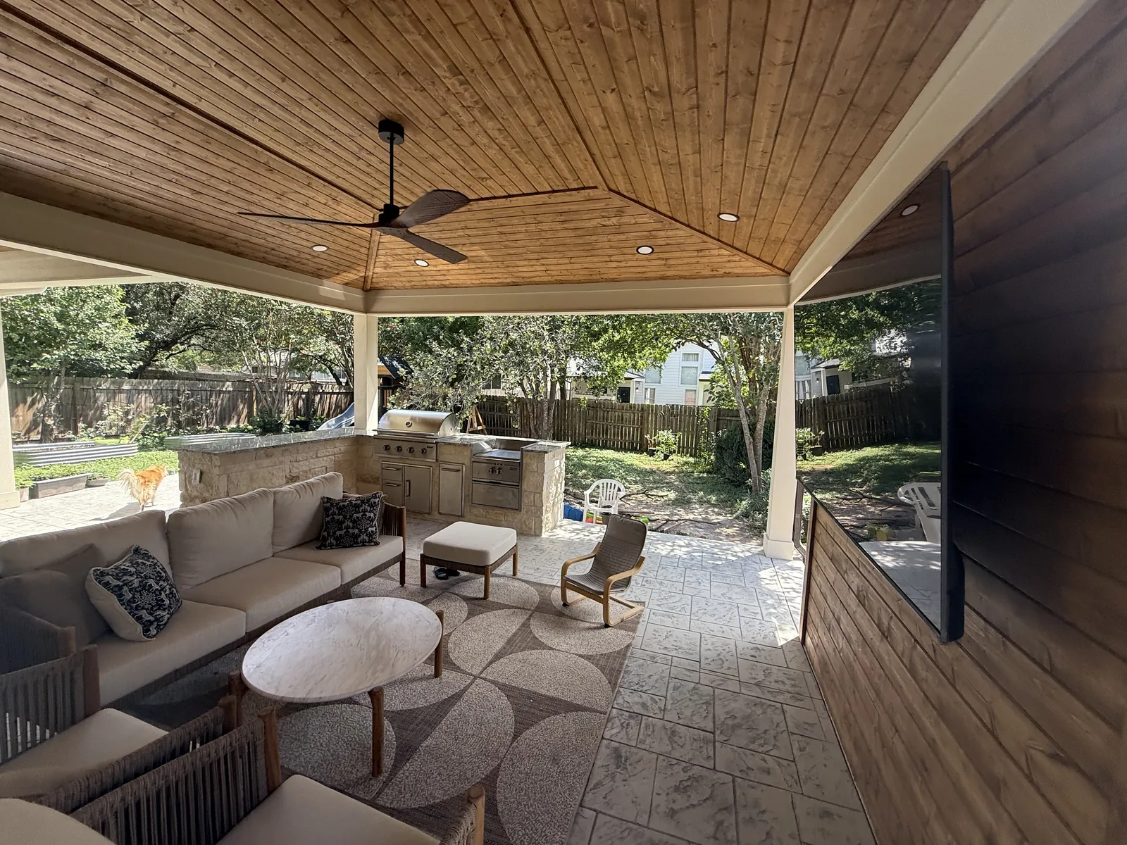 Covered outdoor living space with a stained wood ceiling, ceiling fans and lounge seating