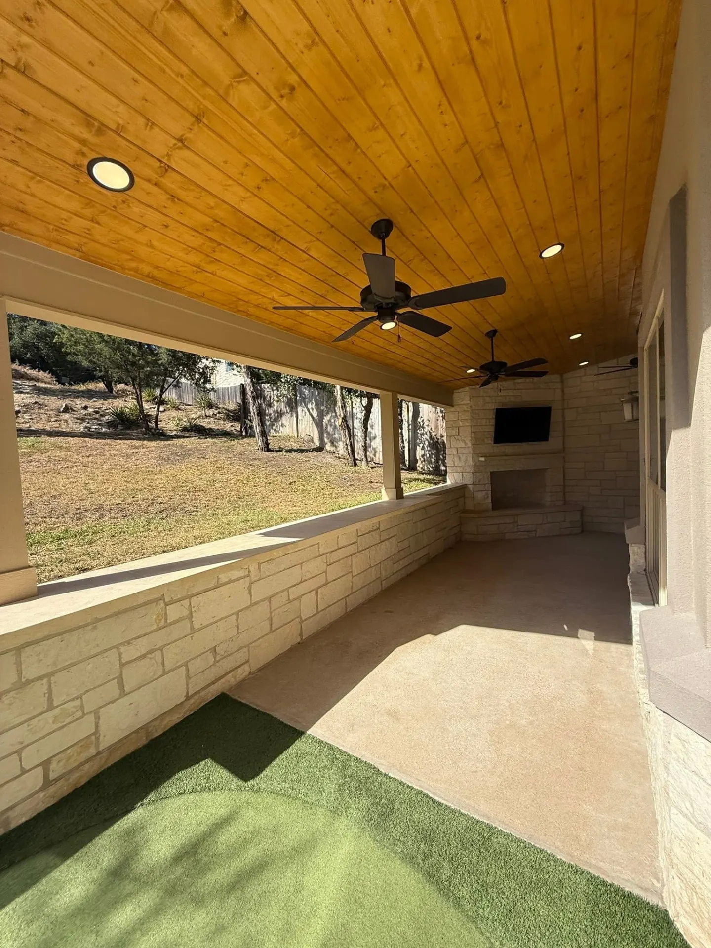 Covered outdoor living room with stone fireplace and vaulted ceiling