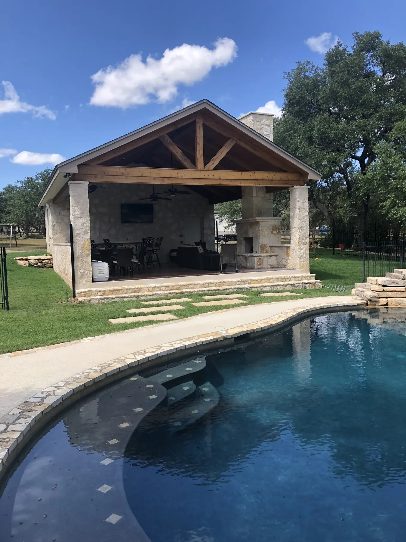 Freestanding stone pavilion beside a swimming pool