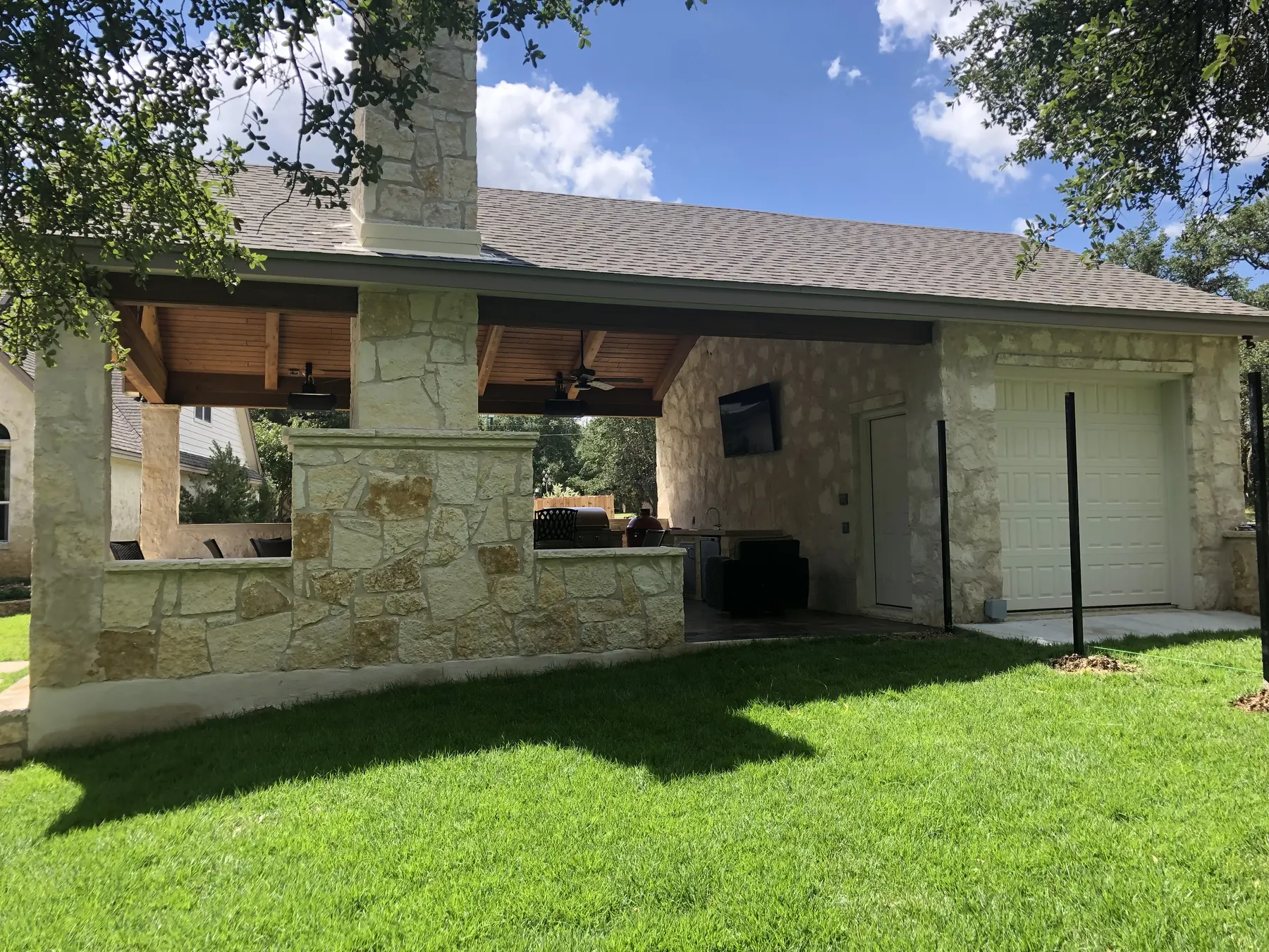 Full freestanding stone pavilion and covered living area seen from the lawn