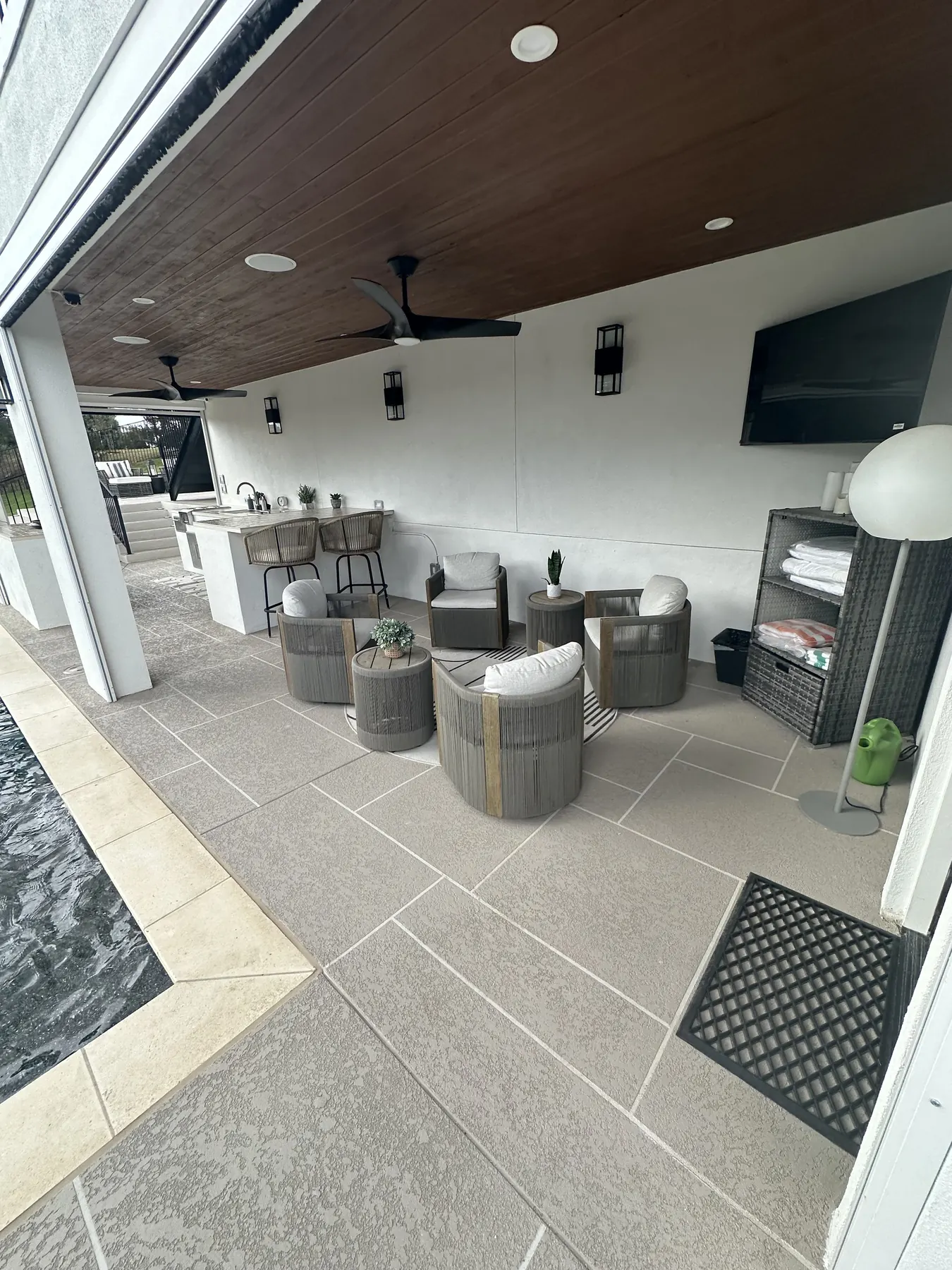 Completed covered lounge with a wood ceiling, seating and mounted television
