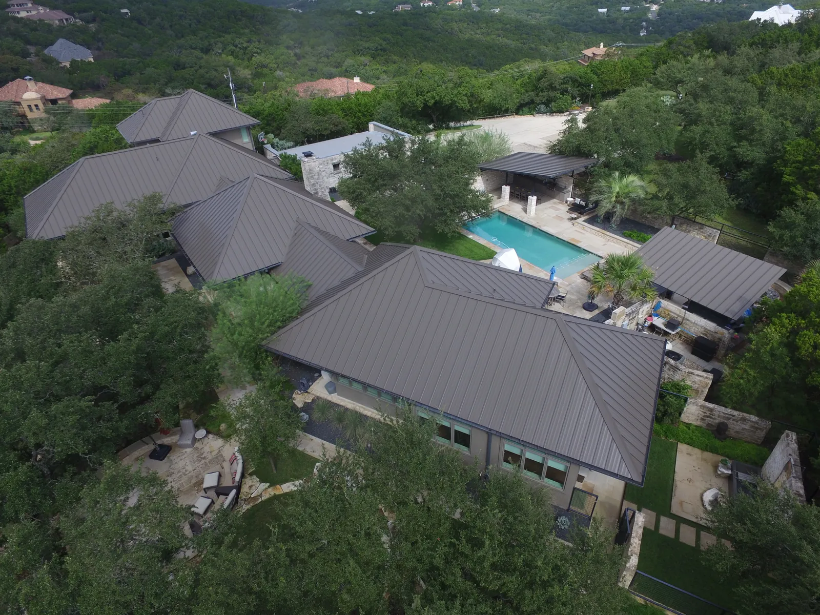 Aerial view of a completed property showing its roofs, pool and backyard