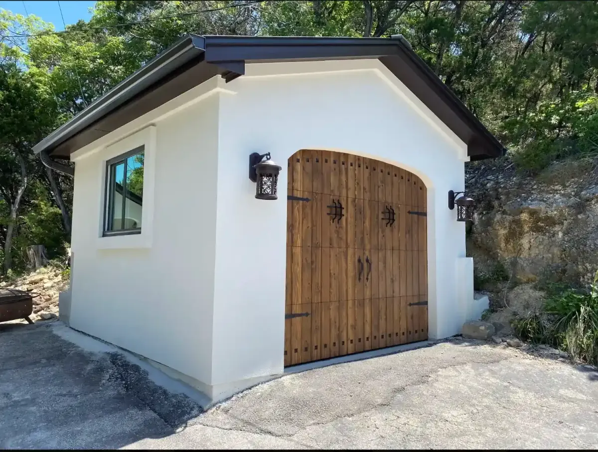 Custom detached garage with wood doors and stucco finish built by TWT on a finished Central Texas property
