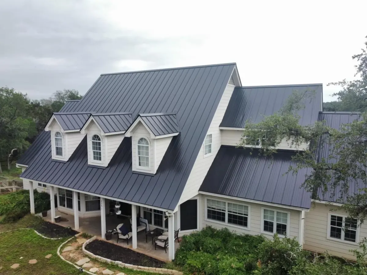 Aerial view of a white Central Texas home with a dark standing-seam metal roof