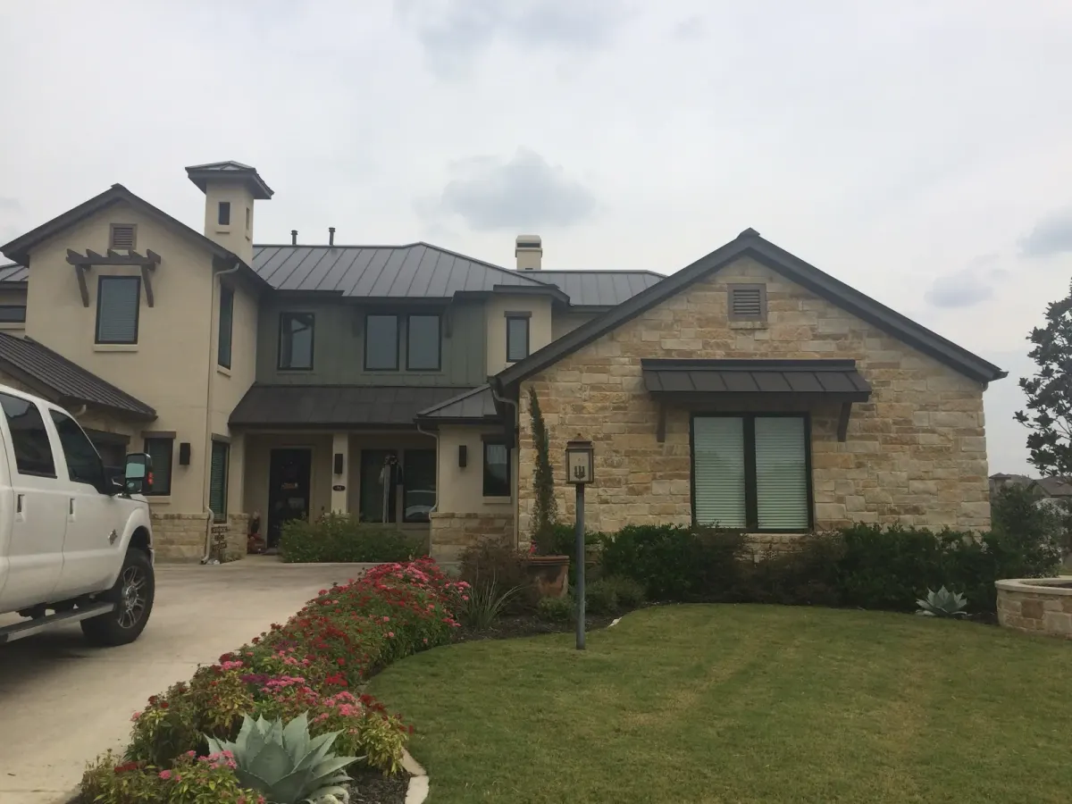Limestone Central Texas home with a completed dark standing-seam metal roof