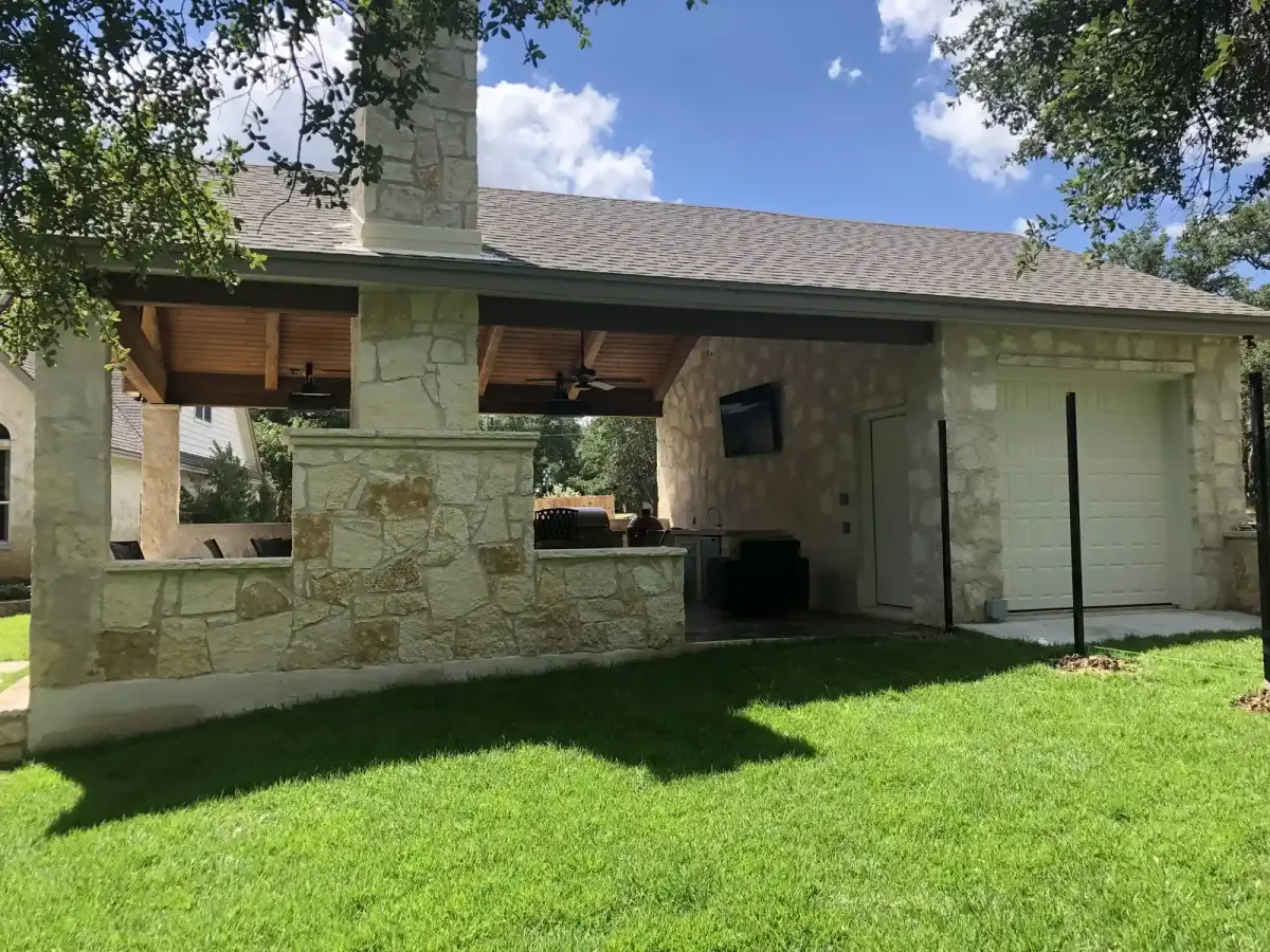 Full freestanding stone pavilion and covered living area seen from the lawn